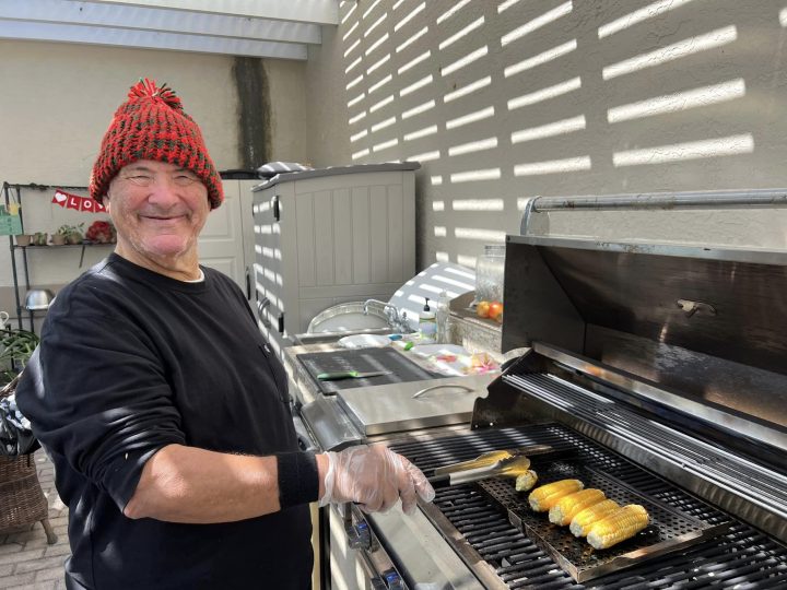 A man wearing an orange hat grilling corn on the grill