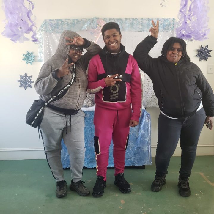 Three people posing in front of a Photo Booth backdrop