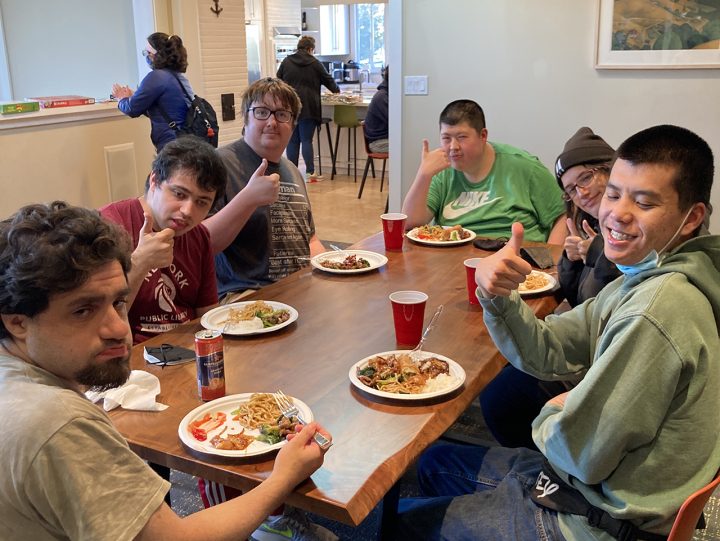 Group of people having dinner and giving the photographer thumbs up
